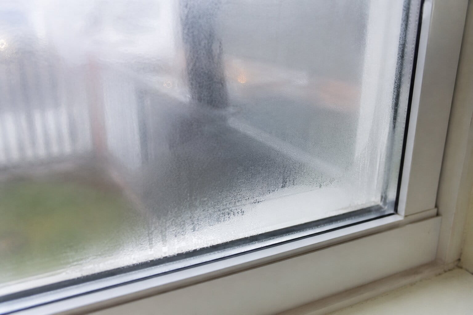 Close-up of a cloudy window pane showing moisture between glass layers