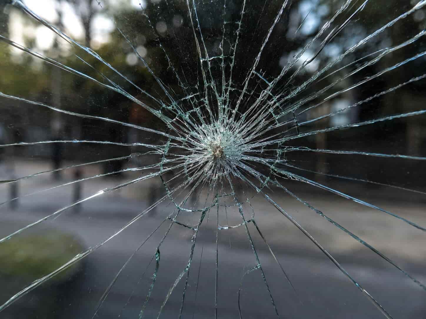 Close-up of an impact crack in a window pane showing a star or spider web pattern