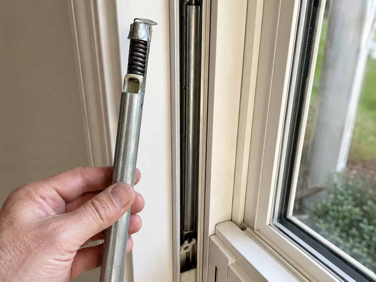 Close-up of a spiral window balance being removed from a vinyl window sash channel